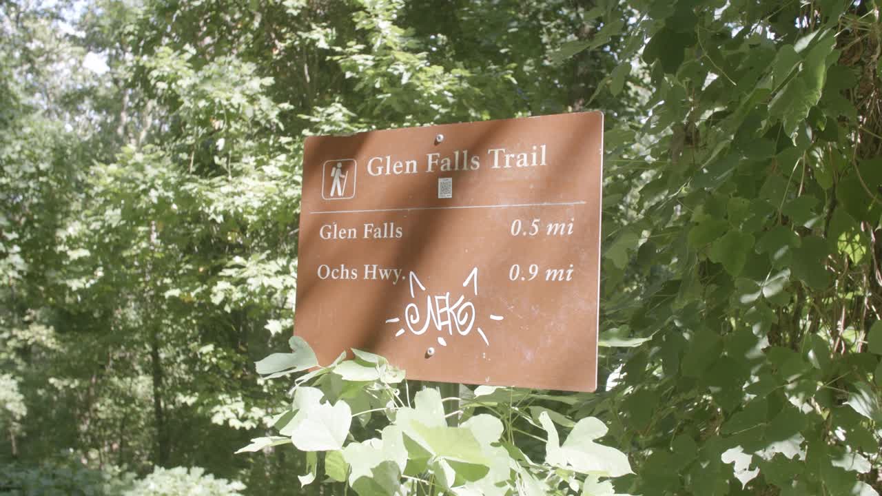 imágenes de un cartel de la naturaleza que dice glenn falls trail con algunos graffiti en chattanooga, tennessee