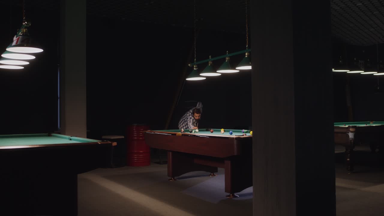 Man playing billiards in a dark pool hall