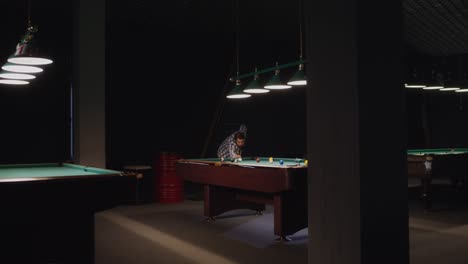 hombre jugando al billar en una sala de billar oscura