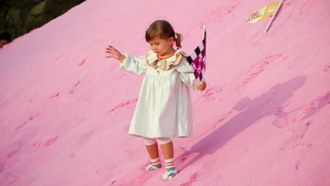 playful child with flag climbs pink sand hill or mount at sunset - herb island park