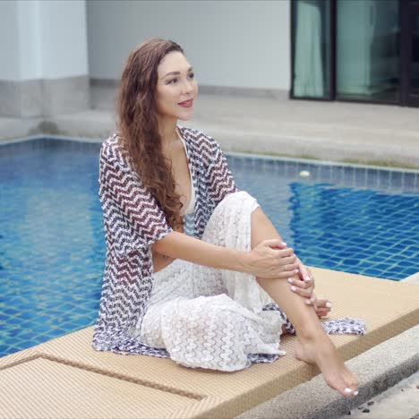 Barefoot-lady-sitting-on-lounger-on-poolside