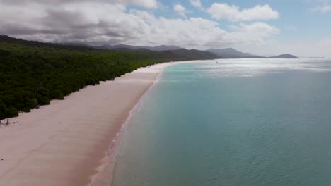 panorámica playa de whitehaven arena blanca velero aéreo drone whitsundays isla airlie parque nacional australia sol soleado sombra de nubes movimiento cielo azul exterior gran barrera de arrecifes azul claro agua océano estático