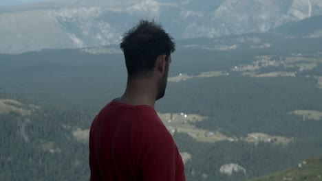 Man-standing-on-a-mountain-top-looking-in-direction-of-snowball