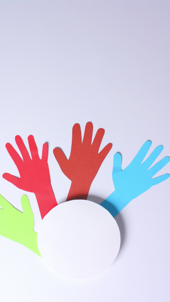 Vertical video of hands around circle made of colourful paper on white background with copy space