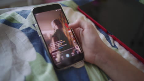 teenage girl using smartphone and tablet on a bed