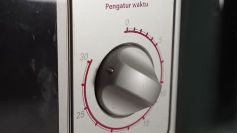 Hand-Turning-Manually-The-Knob-Of-Electric-Microwave-Oven,-Close-Up