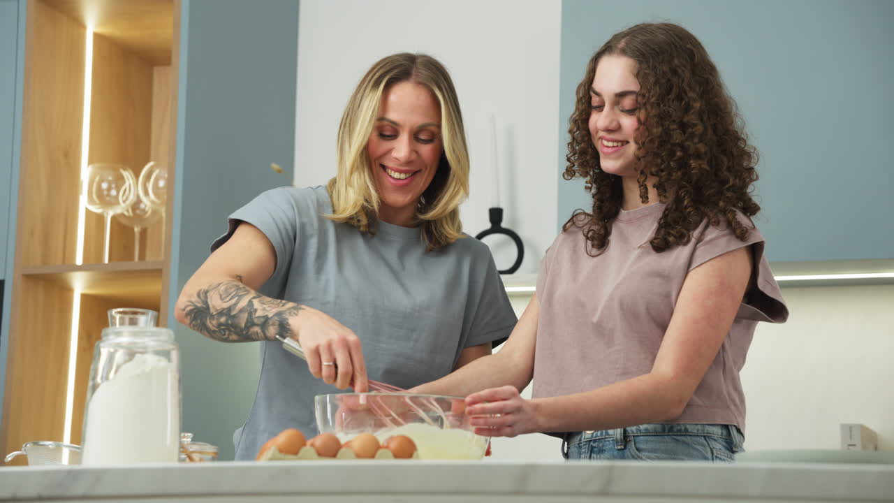 Mother and daughter laughing in slow motion while cooking a dessert