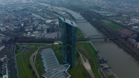 Vista-Aérea-Del-Moderno-Edificio-Futurista-De-Gran-Altura-En-La-Orilla-Del-Río.-Diapositiva-Y-Toma-Panorámica-Del-Rascacielos-Del-Banco-Central-Europeo.-Fráncfort-Del-Meno,-Alemania