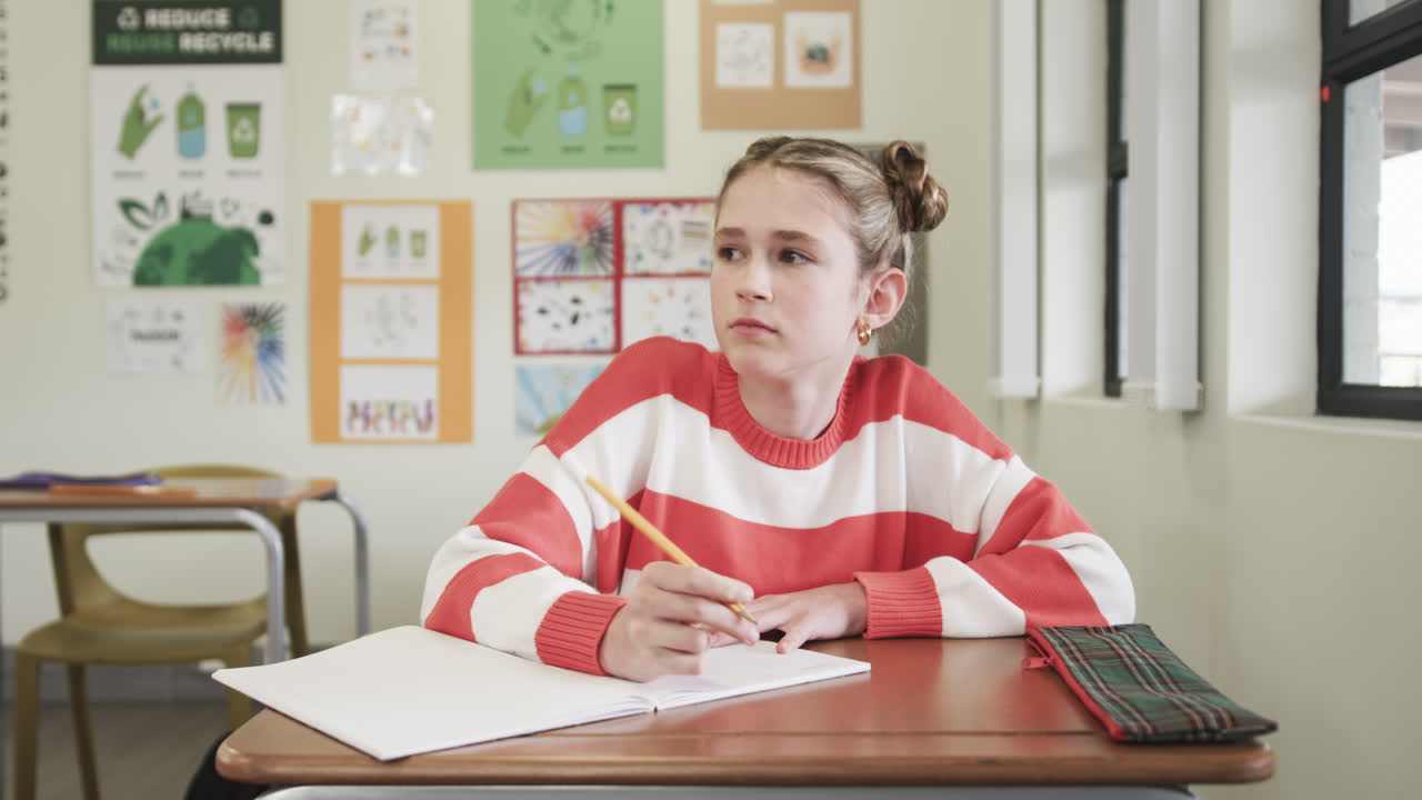 A scuola, giovane ragazza che scrive su un quaderno, concentrata su un compito in classe
