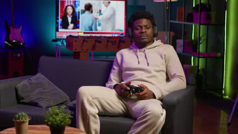 gamer at home sitting down on couch enjoying games on laptop during leisure time. black man sitting on couch in living room, playing video games on notebook, relaxing after work. camera a.