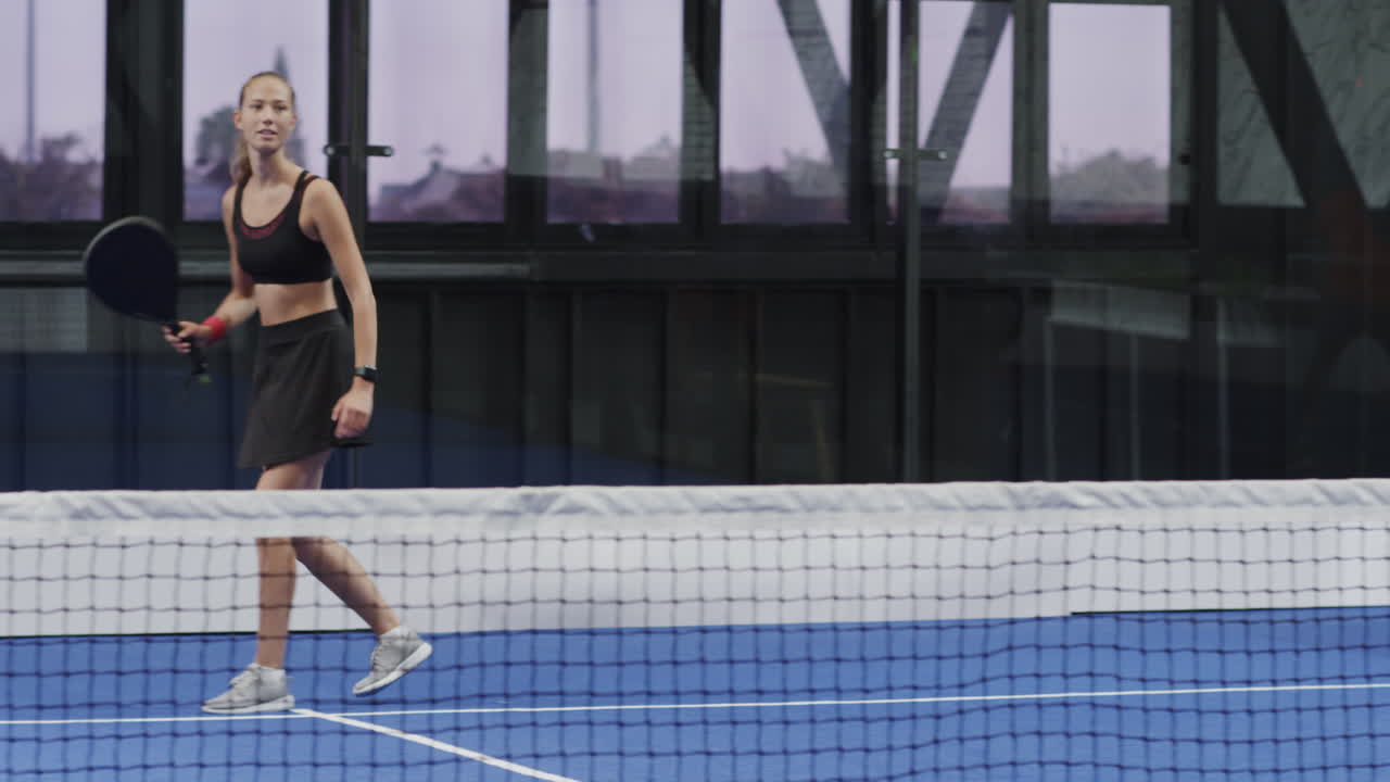 Smiling diverse players enjoying padel tennis match on indoor court, showing teamwork