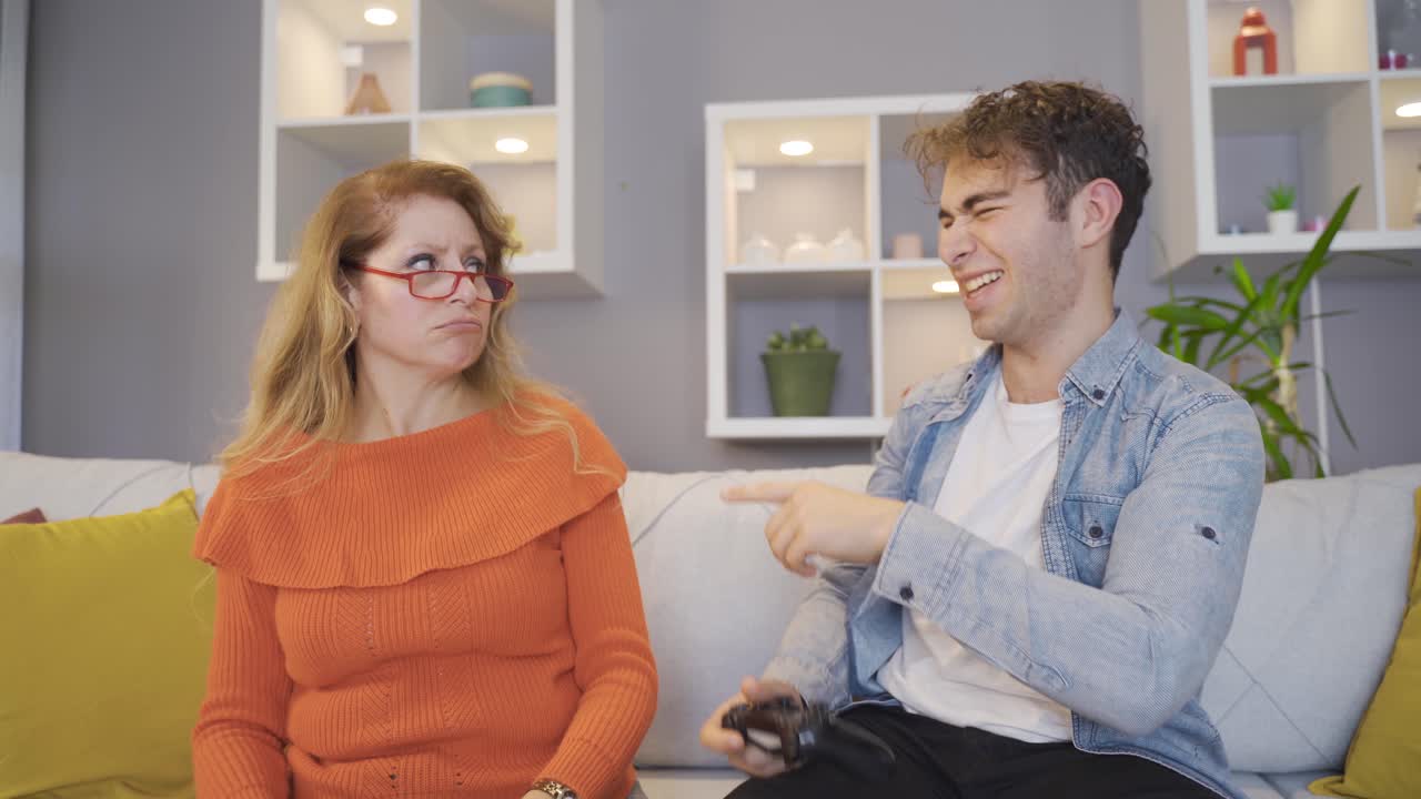 Young man plays with his mother with game consoles.