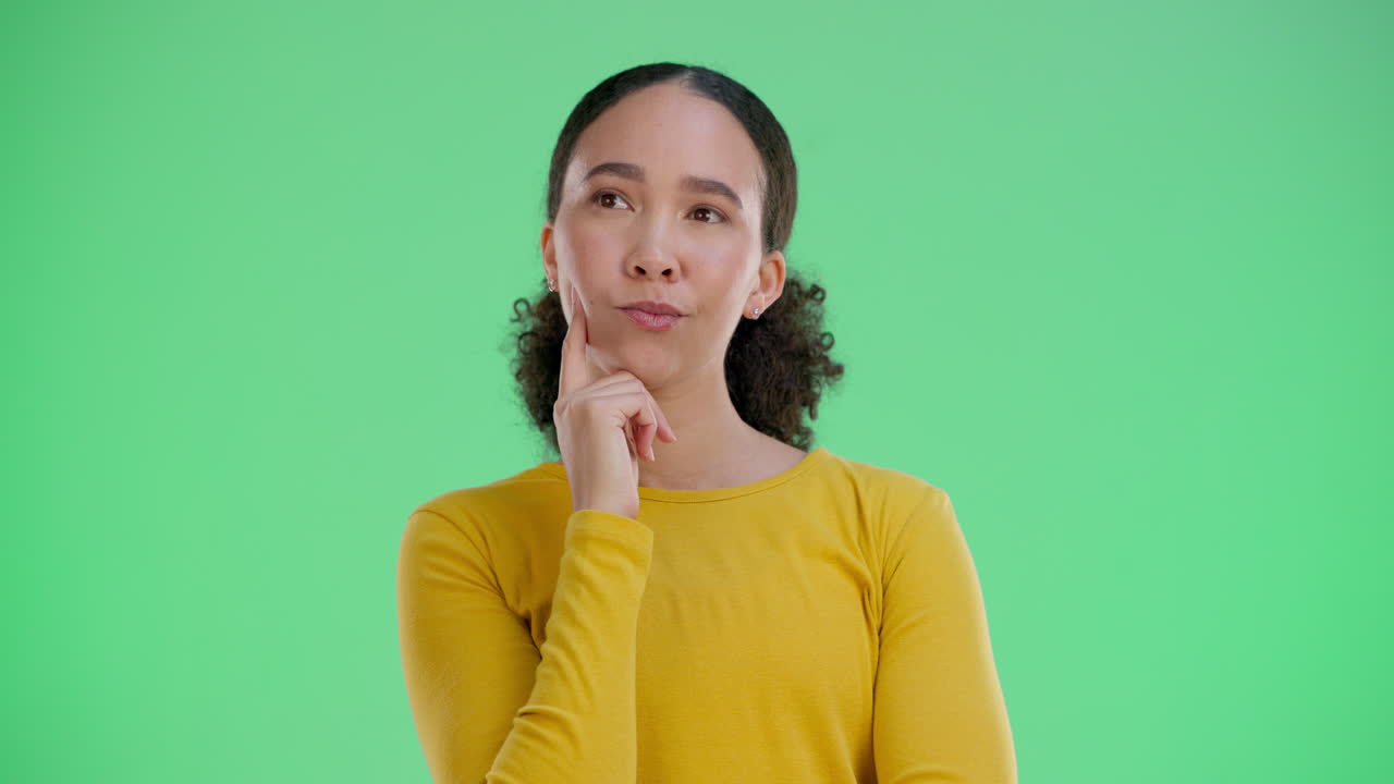 A contemplative woman in front of a green screen