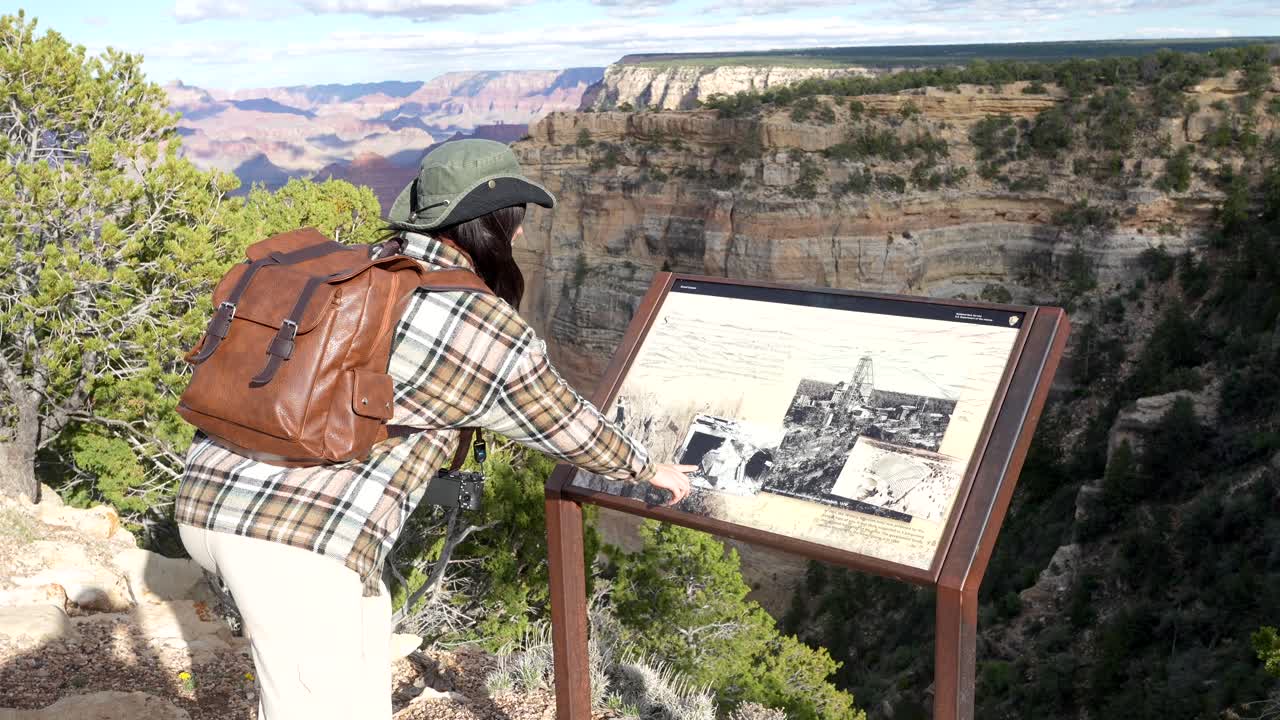 Woman Looking at Informational Sign and Grand Canyon View