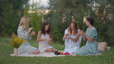 A group of young women in nature together sculpt from clay. Open class joint activity communication laughter common hobby women&#039;s circle.
