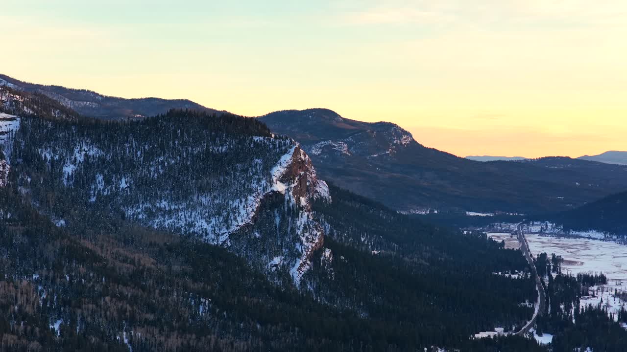 Close-up of the sheer rock face of Treasure Mountain near Wolf Creek Pass. The rugged cliffs feature deep crags and snow-dusted pine trees, showcasing the dramatic geology of the San Juan Mountains