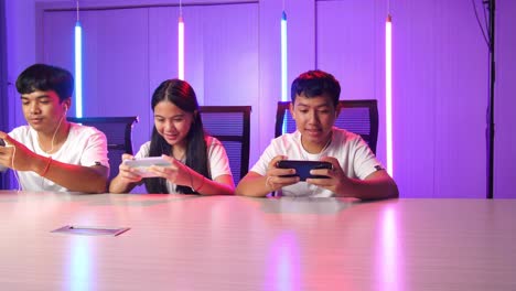 team of asian esport gamers playing in competitive video games on a cyber games tournament by mobile phone and posing