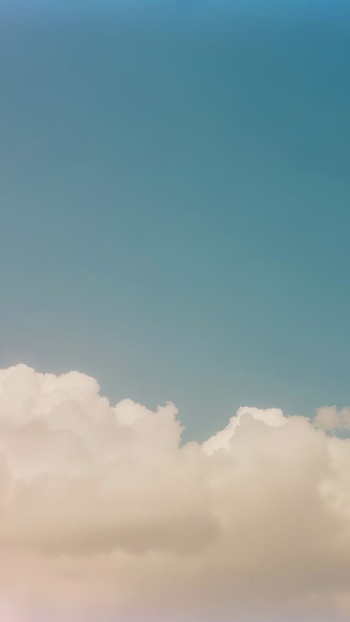 Vertical video: Drifting cumulus bank pushed by wind, sliding right, puffing over teal sky