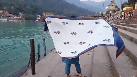 jovem desfrutando na margem do rio ao pôr do sol de um vídeo de ângulo plano é tirado rishikesh uttrakhand índia em 15 de março de 2022