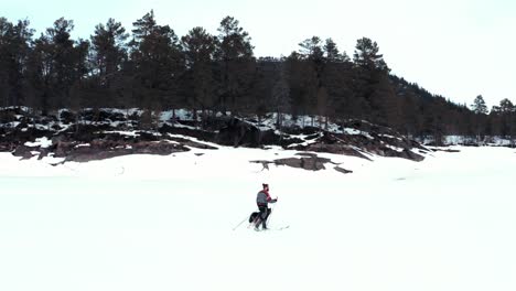 Mann-Im-Ski,-Der-Im-Winter-In-Norwegen-Mit-Seinem-Hund-Durch-Die-Verschneite-Landschaft-Spaziert