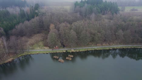 Aerial-view-of-a-lake-in-the-autumn-woods-with-a-path-that-people-walk-through