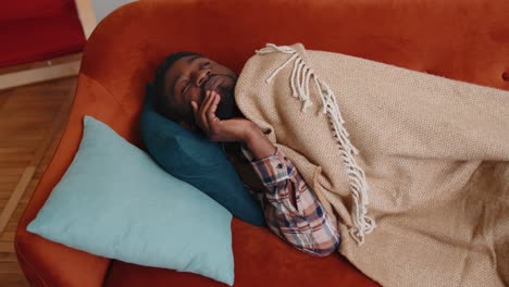 african american young man sleeping quietly in bedroom at home, smiling, lying on comfortable bed