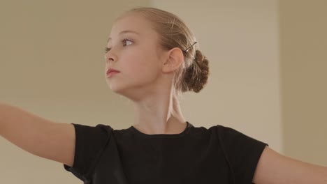 a group of young ballet students in black dancewear practicing positions in a spacious ballet studio with wooden flooring and wall-mounted barres. focused expressions and synchronized movements.