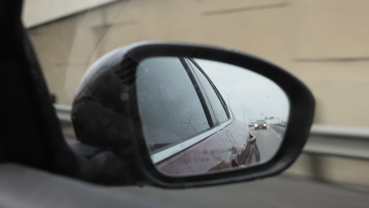 POV looking in to the passenger rearview mirror in a modern sedan