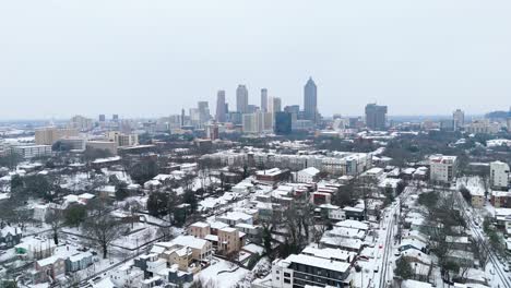 aerial push in on the snow covered suburbs of midtown atlanta georgia with skyscrapers in the background.