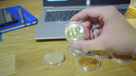 joven hombre de negocios en su oficina sosteniendo bitcoin físico en sus manos
