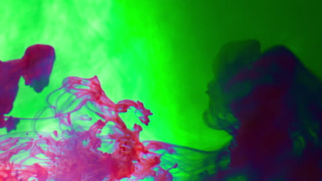 purple and green paint or dye dropped into water against white background to create swirling colourful smoke background 1