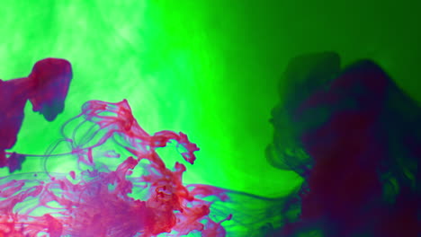 pintura o tinte púrpura y verde caído en el agua contra un fondo blanco para crear un fondo de humo de colores giratorios 1
