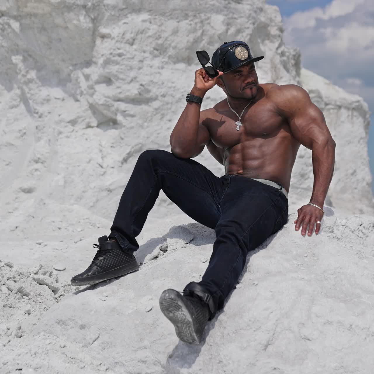 Bodybuilder with naked torso outdoor. Handsome athlete man showing muscles on the rocky mountain