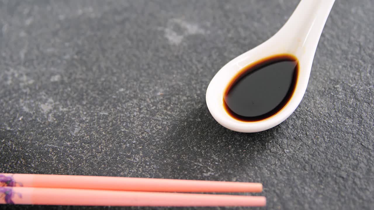 Chopsticks and soy sauce on black stone slate