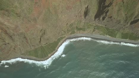 Vista-Aérea-De-Las-Olas-Rompiendo-En-La-Playa-Y-Los-Campos-Cultivados-Cerca-De-La-Costa-En-Cabo-Girão,-Câmara-De-Lobos,-Madeira-Ísland,-Portugal