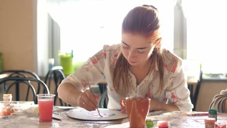 woman painting a wooden disc