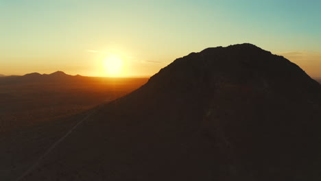 volando desde detrás de un pico de montaña en el desierto de mojave para revelar el sol y luego orbitando alrededor de la montaña para una vista aérea del vasto paisaje