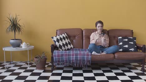 woman using phone on a sofa in a living room