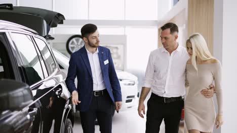 Front-view-of-a-couple-listening-to-car-dealer-in-dealership-discussing-luxurious-new-model