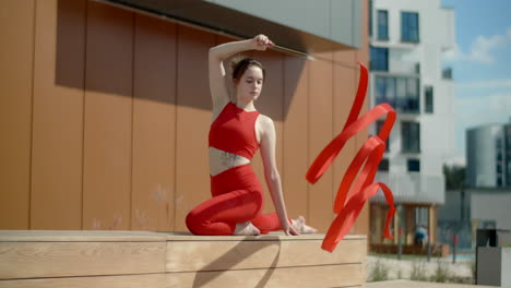 woman performing rhythmic gymnastics with red ribbon