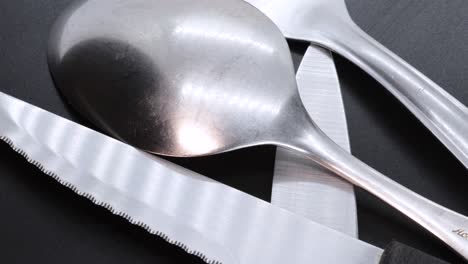 Macro-shot-of-steel-spoon-on-a-black-bacground,-rotating-motion