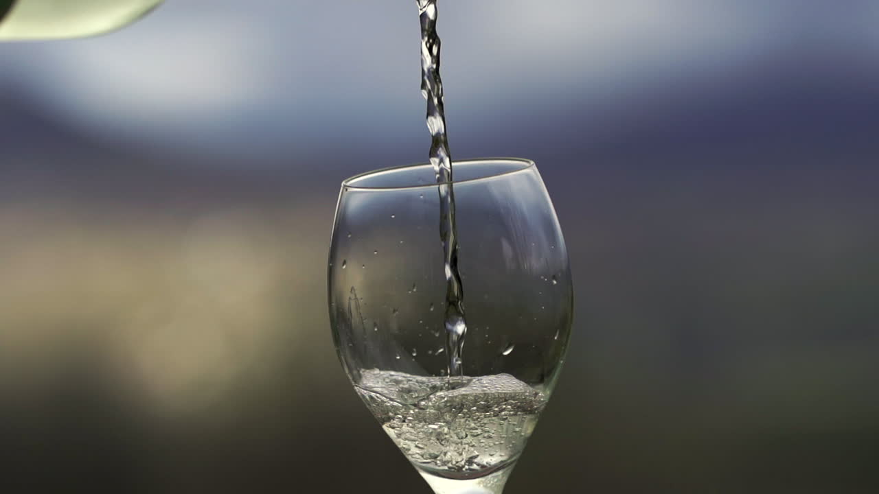 Vino bianco versato al rallentatore in un bicchiere specificamente progettato per vini bianchi