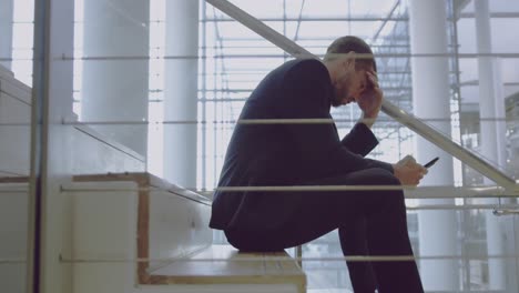 hombre de negocios usando teléfono móvil en las escaleras de la oficina 4k