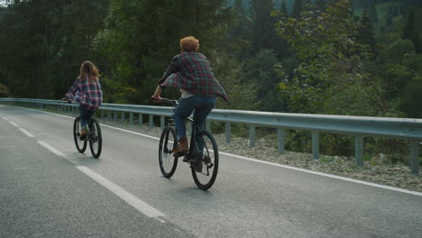 Couple-enjoying-bicycles-trip-on-mountains-highway.-Two-bikers-cycling-on-road.