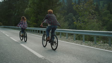 couple enjoying bicycles trip on mountains highway. two bikers cycling on road.