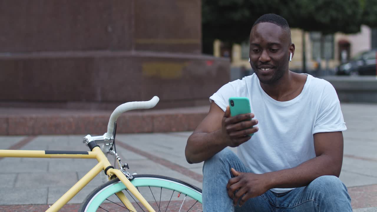 Mann mit Fahrrad, der im Freien ein Mobiltelefon benutzt