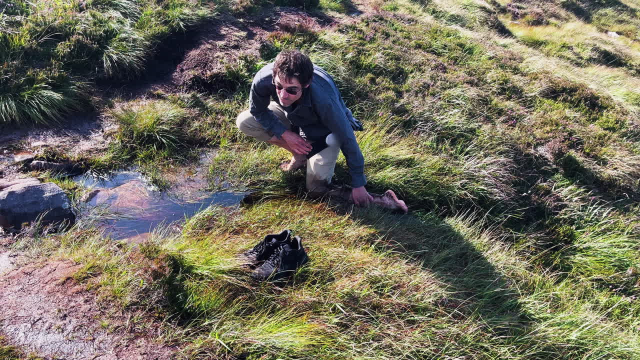 A man washing legs on water stream in rural village of ireland