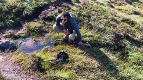a man washing legs on water stream in rural village of ireland