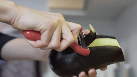 close shot as peeling off the eggplant in the kitchen, holding it in hands