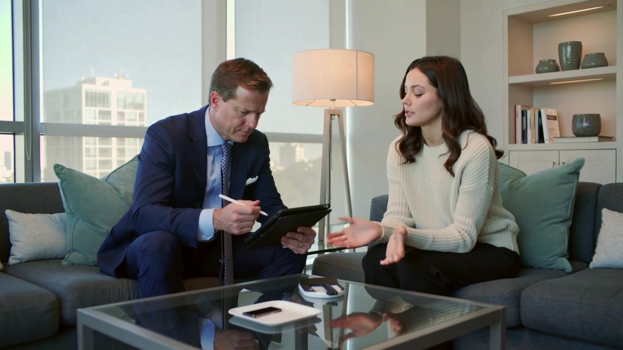Responding to client question, man in navy suit tapping, signing tablet with stylus, office lounge